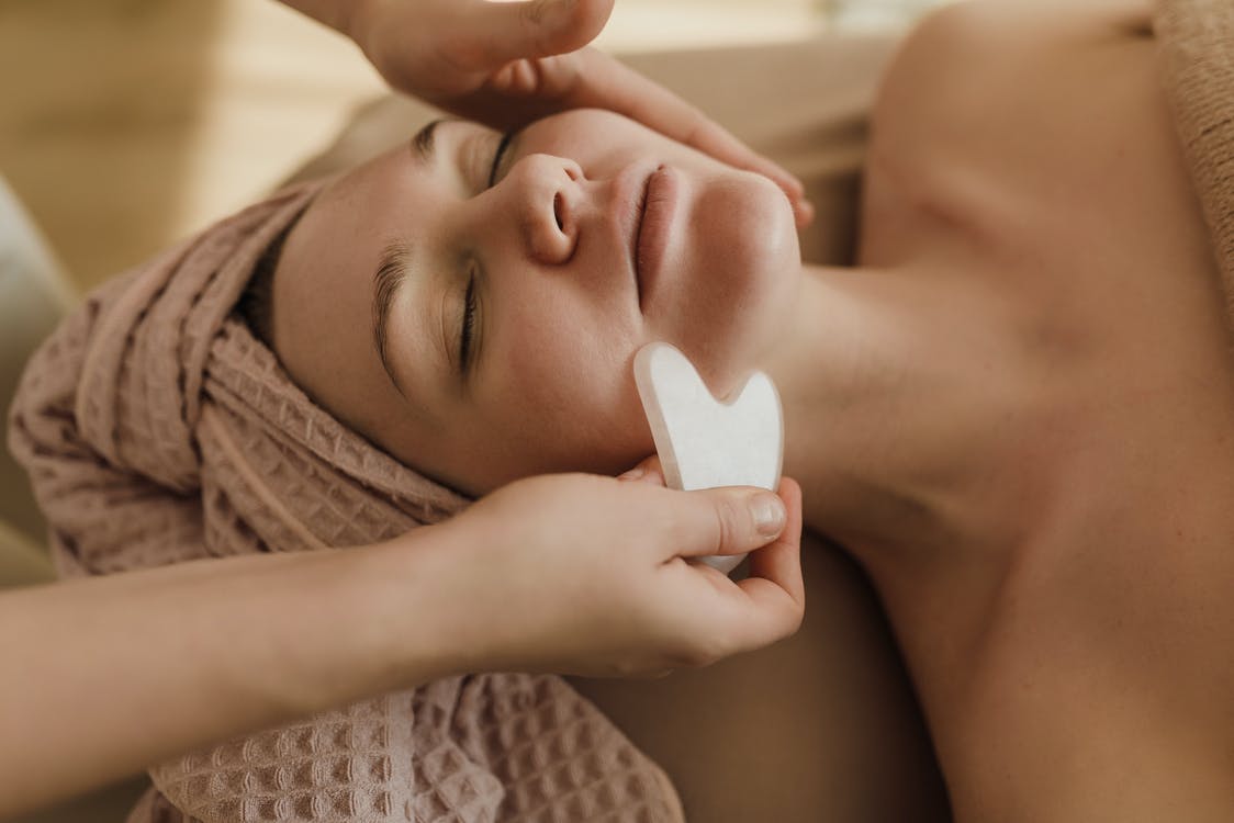 A Person Using a Gua Sha on a Woman's Face