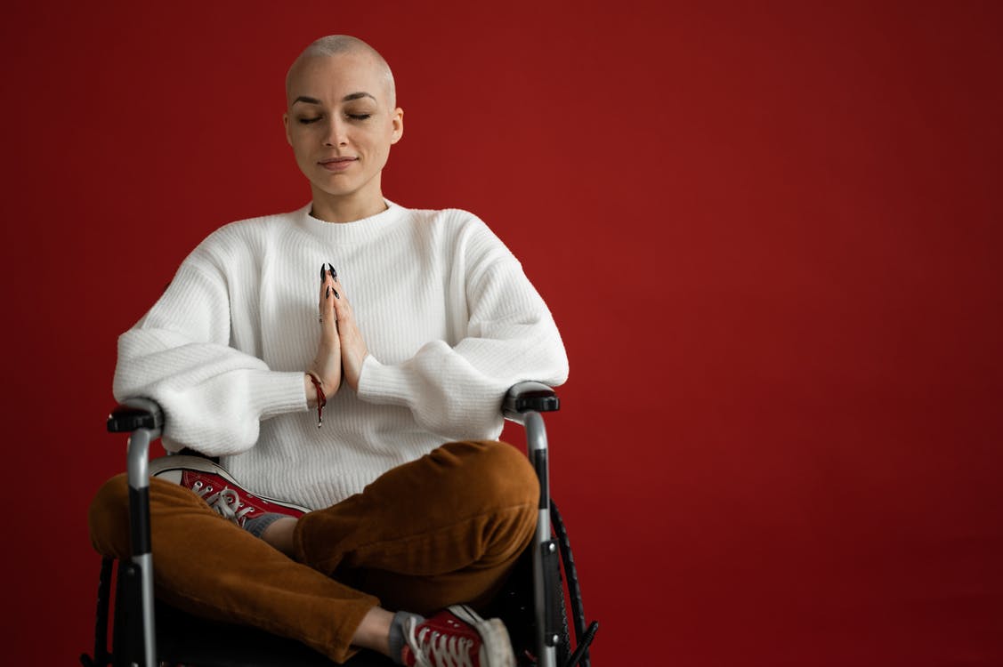 Free Young concentrated female with praying hands and crossed legs meditating during cancer recovery process on red background Stock Photo